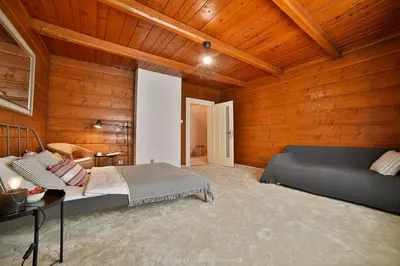 a bedroom with wooden walls and a bed and a table at Zielona willa in Rabka