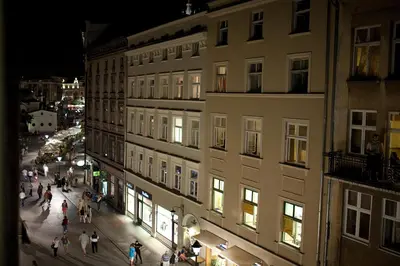 a group of people walking down a street at night at Hotel Jan in Kraków