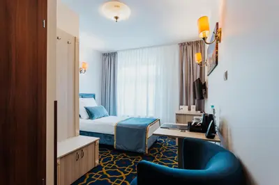 a hotel room with a bed and a blue chair at Hotel Jan in Kraków