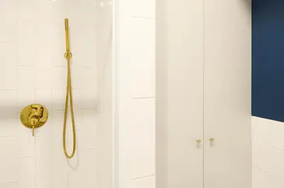a shower with a gold shower head on a wall at Polka Apartment 2-bed in Kraków