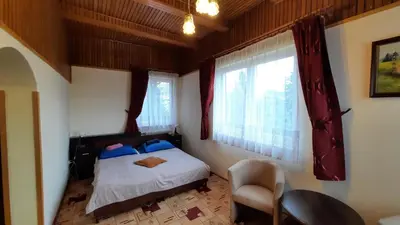 a bedroom with a bed and a chair and windows at Willa Światowid in Rabka