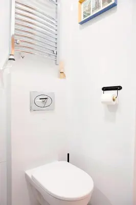 a white bathroom with a toilet and a window at Cosy Apartment in Kraków