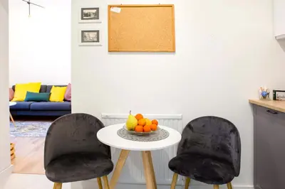 two chairs and a table with a bowl of fruit on it at Cosy Apartment in Kraków