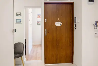 a wooden door in a room with a chair at Cosy Apartment in Kraków