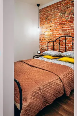 a bed in a room with a brick wall at Cosy Apartment in Kraków