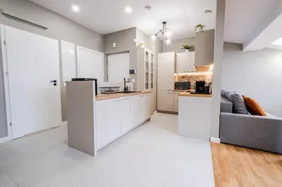 a kitchen with white cabinets and a couch at Old Town Vistula Premium Apartments in Kraków