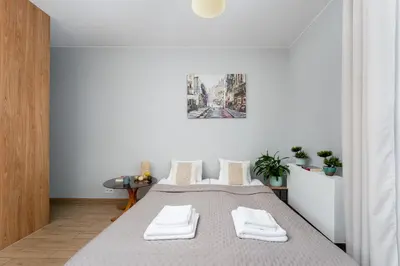 a white room with a bed with two white towels at STEAM PARK Krakow Apartment in Kraków