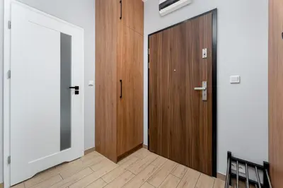a hallway with two wooden doors and a wooden floor at STEAM PARK Krakow Apartment in Kraków