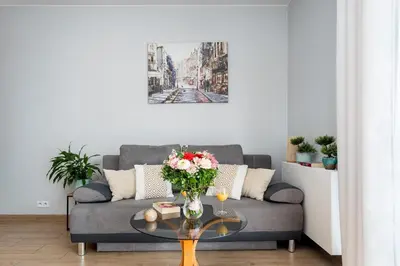 a living room with a couch and a table with flowers at STEAM PARK Krakow Apartment in Kraków