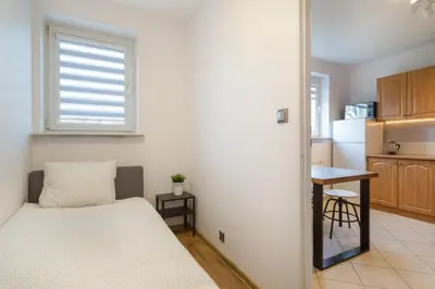 a small bedroom with a bed and a kitchen at Wodna Street Big Family Apartment in Kraków