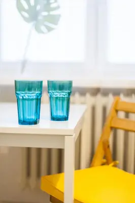 two blue glasses sitting on a table next to a chair at Vintage Krasińskiego 7/4 Apartment in Kraków