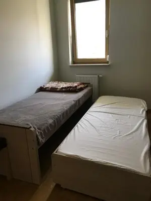 two beds in a small room with a window at Appartement Nowa Huta in Kraków