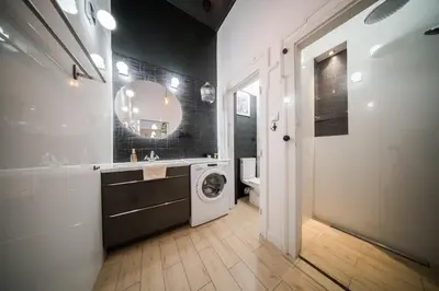 a kitchen with white cabinets and a table in it at Roller Aparthotel in Kraków