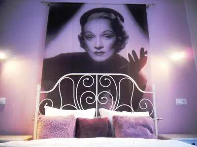 a large painting of a woman is above a bed at Apartamenty Lili & Country in Kraków