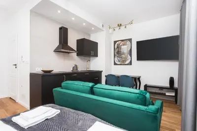 a living room with a green couch and a kitchen at City of the Kings - Nubium Apartment in Kraków