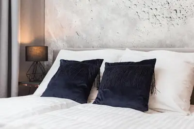 a bed with white sheets and blue pillows at City of the Kings - Nubium Apartment in Kraków