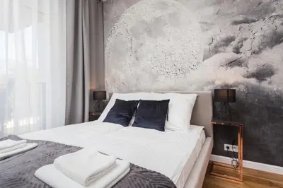 a bedroom with a bed with white sheets and blue pillows at City of the Kings - Nubium Apartment in Kraków