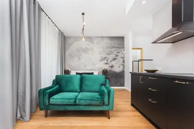 a green chair in a room with a kitchen at City of the Kings - Nubium Apartment in Kraków