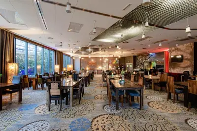a dining room with tables and chairs and windows at Hotel Lenart in Wieliczka