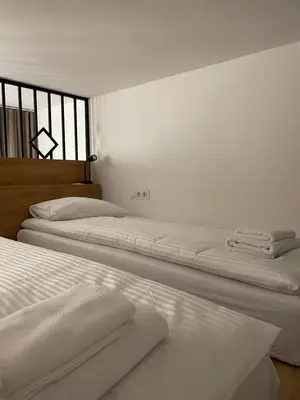 two beds in a white room with white sheets at Kurkowa GamaHome Cozy Apartments in Kraków