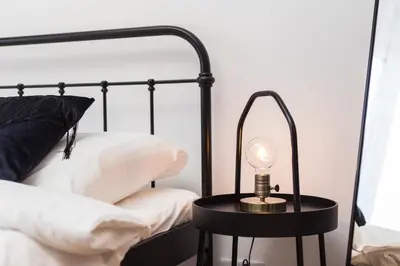 a lamp on a table next to a bed at City of the Kings - Botany Bay Apartment in Kraków