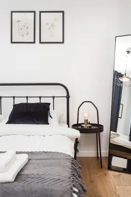 a bedroom with a black and white bed and a table at City of the Kings - Botany Bay Apartment in Kraków