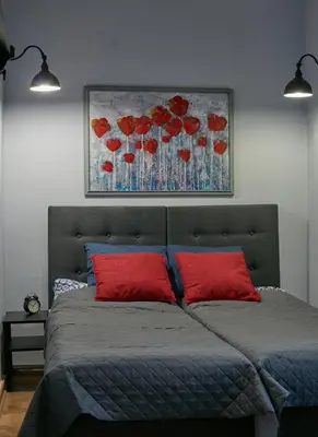 a bedroom with a bed with red pillows and a painting at Stylish apartment in Krakow - Old Town in Kraków