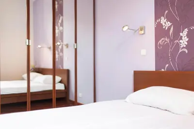 a bedroom with a white bed and a mirror at DaVinci Radziwiłłowska Apartments in Kraków