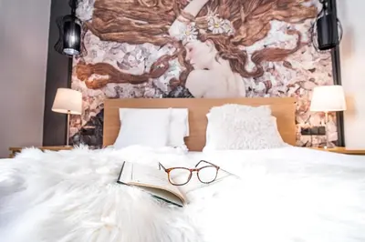 a bed with a book and glasses on it at AT Krakow Apartments in Kraków