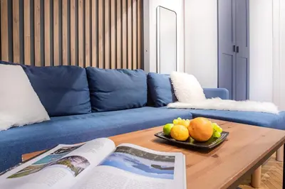 a blue couch with a table with a plate of fruit on it at AT Krakow Apartments in Kraków
