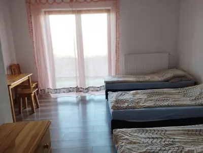 a room with three beds and a desk and a window at Noclegi Pod Dębem in Skawina