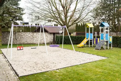 a playground with a swing set in a yard at Apartamenty w Dworku Cheval in Kraków