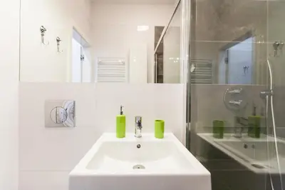 a white bathroom with a sink and a shower at Vintage Tomasza Apartment in Kraków