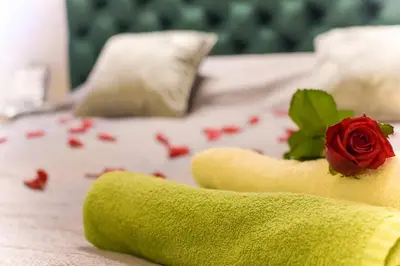 a rose in a towel on a bed with confeder at Apartment Jacuzzi in Kraków