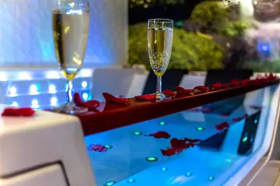 two glasses of champagne on a table with red roses at Apartment Jacuzzi in Kraków