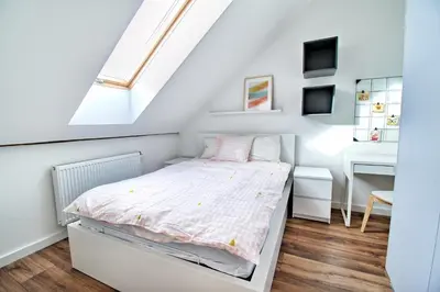 a white bedroom with a bed and a window at City Life Apartments Kraków in Kraków