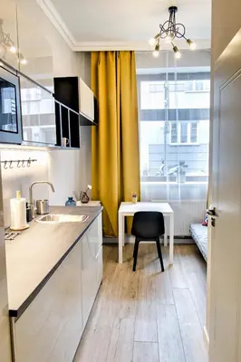a kitchen with a table and a yellow curtain at City Life Apartments Kraków in Kraków