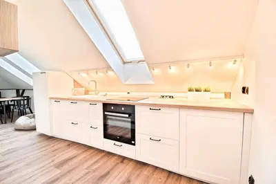 a kitchen with white cabinets and a skylight at City Life Apartments Kraków in Kraków