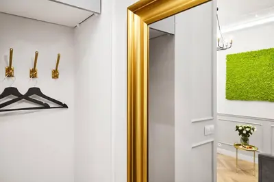a door with a gold frame in a white hallway at HOUSEHOST Apartment I: Studencka Street in Kraków