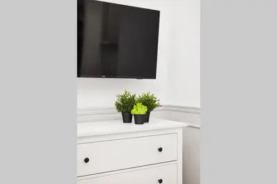 a white dresser with a flat screen tv on top at HOUSEHOST Apartment I: Studencka Street in Kraków