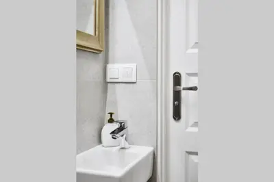 a bathroom with a sink and a mirror next to a door at HOUSEHOST Apartment I: Studencka Street in Kraków