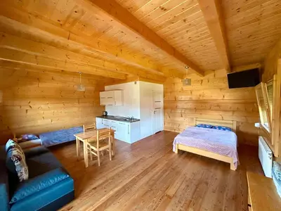 a room with a bed and a kitchen in a log cabin at Domki góralskie na Podhalu Zakopane in Tokarnia