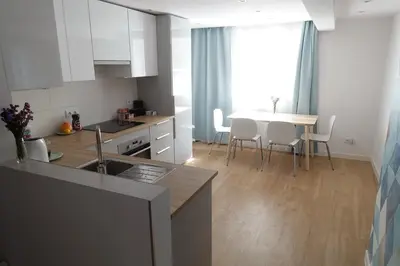 a kitchen with white cabinets and a table with chairs at Three Rooms Apartment in Kraków