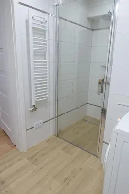 a shower with a glass door in a bathroom at Three Rooms Apartment in Kraków