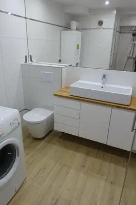 a white bathroom with a sink and a washing machine at Three Rooms Apartment in Kraków