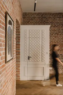a woman walking past a white door in a brick wall at LaRry BirD Old Town by WillyWalls in Kraków