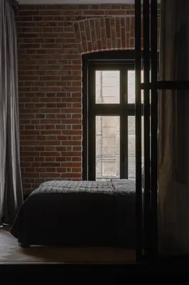 a bedroom with a bed in front of a brick wall at LaRry BirD Old Town by WillyWalls in Kraków