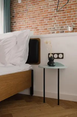 a bed with a side table next to a brick wall at LaRry BirD Old Town by WillyWalls in Kraków