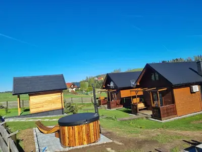 a group of wooden cabins in a field at Domki na Zagroniu in Koninki