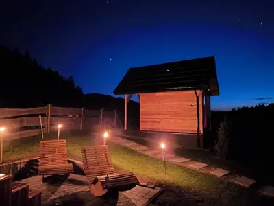 two chairs sitting in front of a building at night at Domki na Zagroniu in Koninki